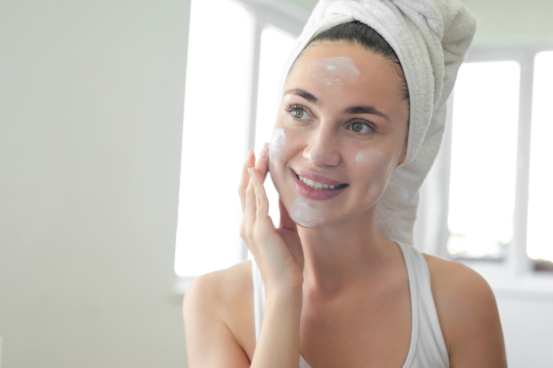 Woman putting face cream on her face